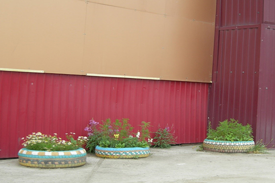 Flowers growing inside old tires that are decorated colorfully.
