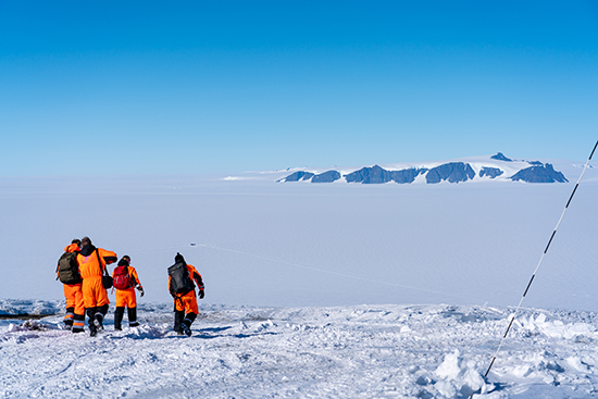 Researchers walking in snowy scenery in Antarctica.